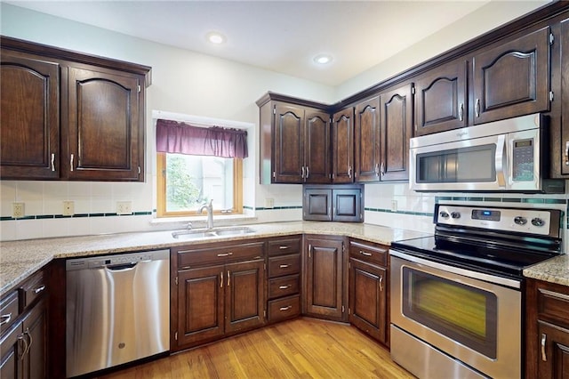 1404 NE Piedmont Dr, Lees Summit, MO 64064 - kitchen with stainless steel appliances, a sink, light wood finished floors, dark brown cabinetry, and tasteful backsplash