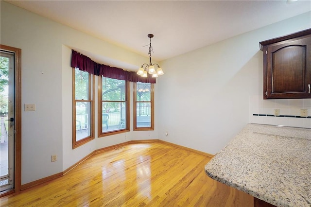 1404 NE Piedmont Dr, Lees Summit, MO 64064 - unfurnished dining area with light wood-style floors, a chandelier, and baseboards