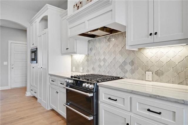 16394 S Loiret St, Olathe, KS 66062 - kitchen with double oven range, custom range hood, white cabinets, arched walkways, and decorative backsplash