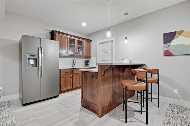 16394 S Loiret St, Olathe, KS 66062 - kitchen featuring stainless steel fridge with ice dispenser, a breakfast bar, glass insert cabinets, backsplash, and pendant lighting
