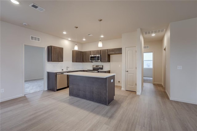 27027 E Oak View Dr, Lees Summit, MO 64086 - kitchen featuring appliances with stainless steel finishes, dark brown cabinets, light wood finished floors, a center island, and backsplash