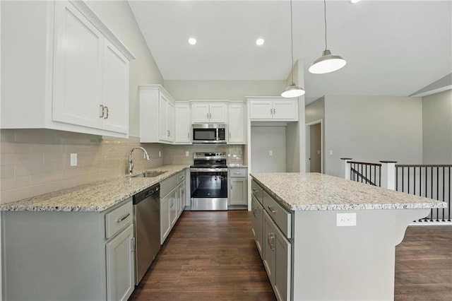 789 Highland Dr, Edwardsville, KS 66111 - kitchen with appliances with stainless steel finishes, a sink, dark wood-style floors, a kitchen island, and decorative backsplash