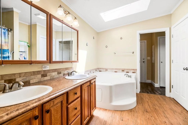 415 E Hulett St, Edgerton, KS 66021 - full bathroom featuring a skylight, wood finished floors, a garden tub, double vanity, and crown molding