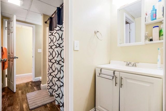 415 E Hulett St, Edgerton, KS 66021 - bathroom with wood finished floors, vanity, a paneled ceiling, baseboards, and a shower with curtain