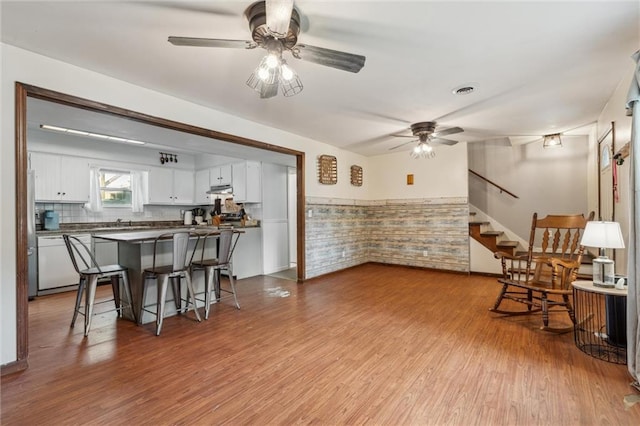 917 L St, Atchison, KS 66002 - kitchen with a ceiling fan, white dishwasher, white cabinetry, wood finished floors, and a breakfast bar