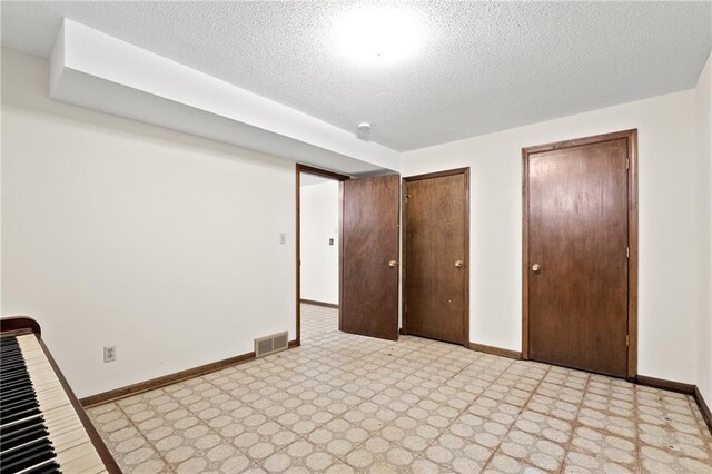 120 Highland Rd, Lansing, KS 66043 - unfurnished bedroom with two closets, baseboards, a textured ceiling, and light floors
