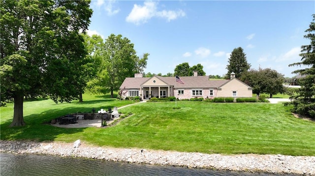 450 Ruth Ewing Rd, Liberty, MO 64068 - view of front of house featuring a fire pit, a water view, a front lawn, and a chimney
