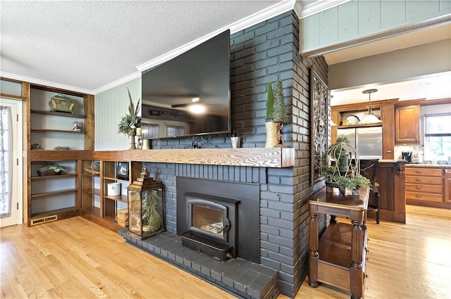450 Ruth Ewing Rd, Liberty, MO 64068 - living room featuring ornamental molding, light wood-style floors, a textured ceiling, and a brick fireplace