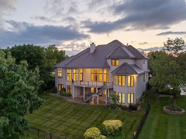 14005 Dearborn St, Overland Park, KS 66223 - back of property at dusk featuring a patio area, stucco siding, stairway, and a chimney