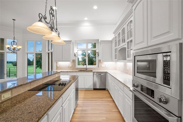 14005 Dearborn St, Overland Park, KS 66223 - kitchen featuring appliances with stainless steel finishes, ornamental molding, white cabinets, light wood finished floors, and a chandelier
