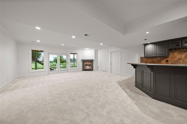 14005 Dearborn St, Overland Park, KS 66223 - unfurnished living room featuring crown molding, recessed lighting, light colored carpet, and a warm lit fireplace