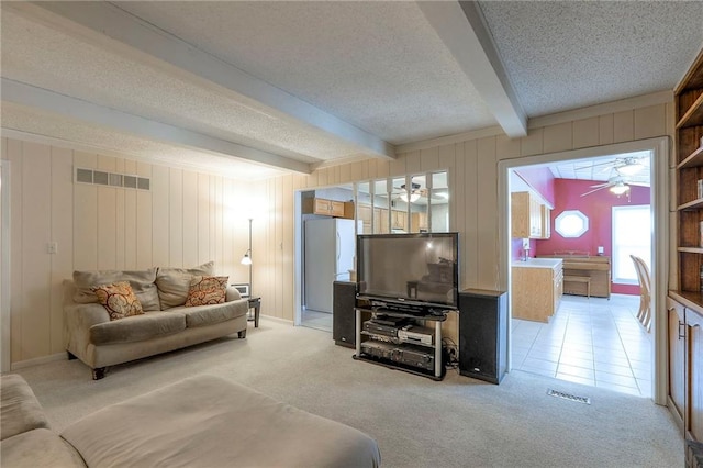 300 S Silver Top Ln, Raymore, MO 64083 - living area featuring ceiling fan, beamed ceiling, a textured ceiling, light carpet, and wood walls