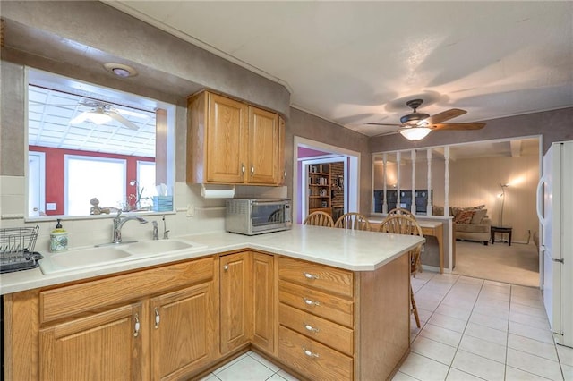 300 S Silver Top Ln, Raymore, MO 64083 - kitchen featuring a ceiling fan, a peninsula, freestanding refrigerator, light countertops, and light tile patterned floors