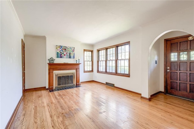 5301 Sycamore Dr, Roeland Park, KS 66205 - unfurnished living room featuring arched walkways, light wood-style flooring, ornamental molding, and a fireplace with flush hearth