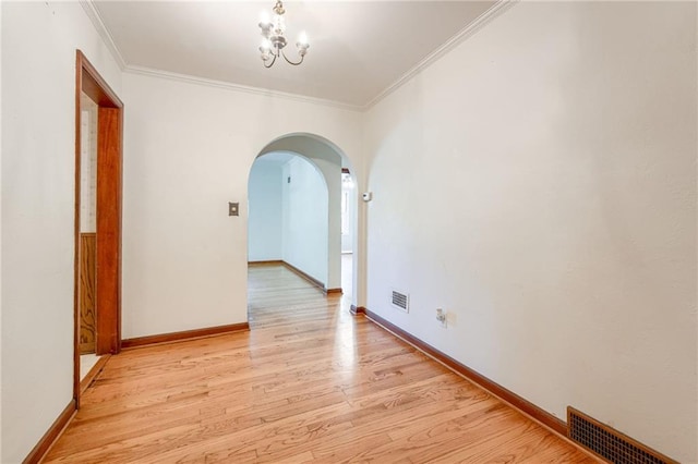 5301 Sycamore Dr, Roeland Park, KS 66205 - empty room featuring arched walkways, ornamental molding, light wood finished floors, and a chandelier
