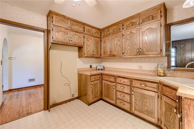 5301 Sycamore Dr, Roeland Park, KS 66205 - kitchen featuring arched walkways, light countertops, ceiling fan, brown cabinetry, and light flooring