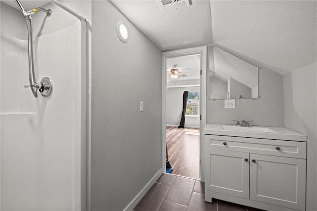 915 4th Ave, Leavenworth, KS 66048 - bathroom featuring a shower, vanity, a textured ceiling, ceiling fan, and tile patterned flooring
