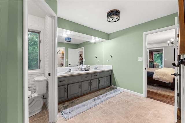 26725 S Bennett Rd, Freeman, MO 64746 - full bathroom featuring connected bathroom, double vanity, toilet, baseboards, and a chandelier