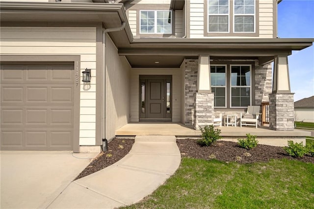 11487 S Cornice St, Olathe, KS 66061 - view of exterior entry with a porch, stone siding, an attached garage, and driveway