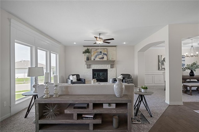 11487 S Cornice St, Olathe, KS 66061 - carpeted living area with a ceiling fan, arched walkways, a large fireplace, a chandelier, and baseboards