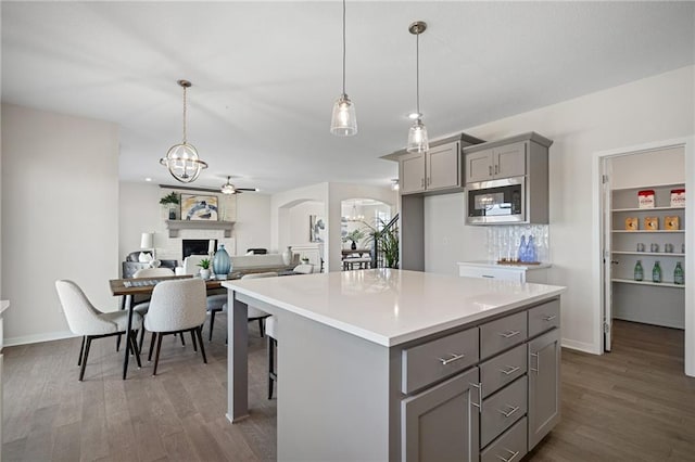 11487 S Cornice St, Olathe, KS 66061 - kitchen featuring gray cabinetry, stainless steel microwave, dark wood-style floors, and a center island