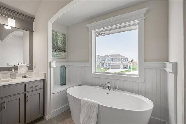 11487 S Cornice St, Olathe, KS 66061 - bathroom featuring wainscoting, vanity, a soaking tub, plenty of natural light, and a decorative wall