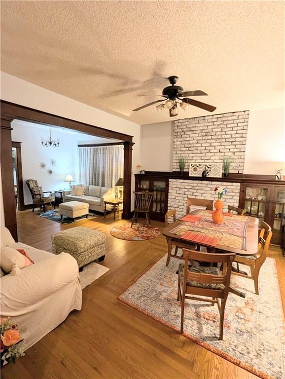 429 N 12th St, Fredonia, KS 66736 - living area featuring a textured ceiling, ceiling fan, a brick fireplace, a chandelier, and wood finished floors