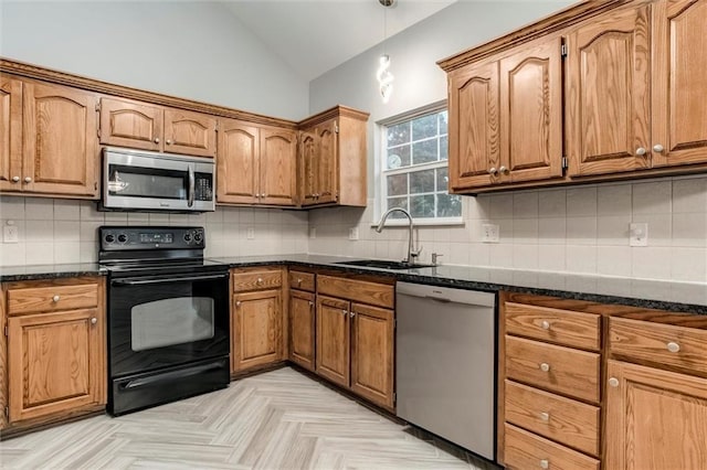 7132 Woodstock St, Shawnee, KS 66218 - kitchen featuring stainless steel appliances, a sink, vaulted ceiling, brown cabinets, and dark stone countertops
