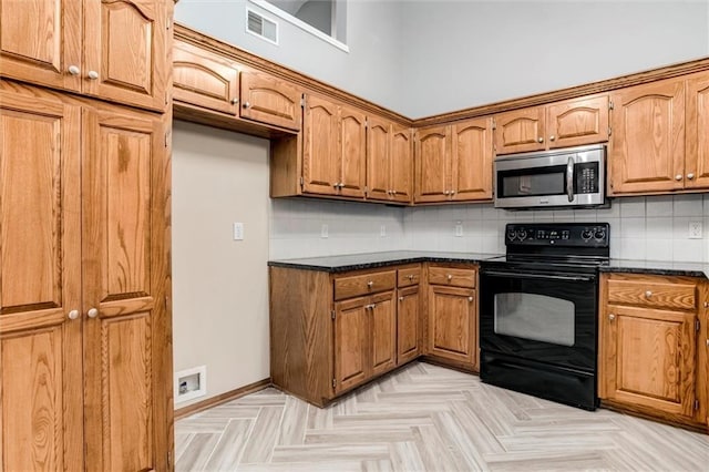 7132 Woodstock St, Shawnee, KS 66218 - kitchen featuring stainless steel microwave, black / electric stove, brown cabinetry, and tasteful backsplash