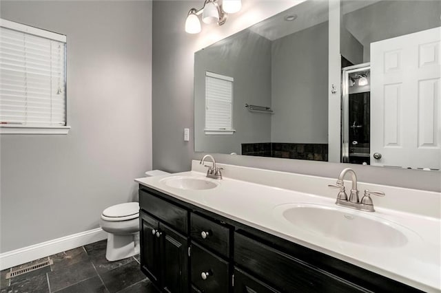 7132 Woodstock St, Shawnee, KS 66218 - bathroom featuring baseboards, double vanity, toilet, and a shower with door