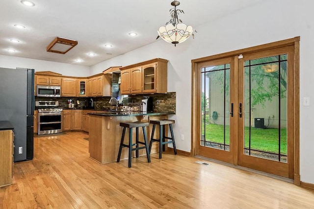 600 N Oak St, Gardner, KS 66030 - kitchen featuring appliances with stainless steel finishes, a peninsula, plenty of natural light, glass insert cabinets, and recessed lighting