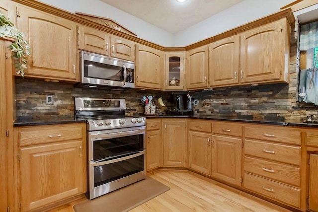 600 N Oak St, Gardner, KS 66030 - kitchen with stainless steel appliances, decorative backsplash, light wood-style floors, glass insert cabinets, and dark stone countertops