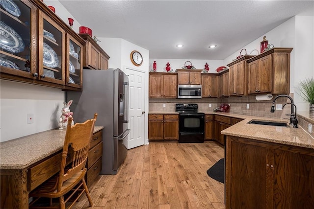14165 Ashbury Ct, Basehor, KS 66007 - kitchen with stainless steel appliances, a sink, light wood-type flooring, backsplash, and light stone countertops