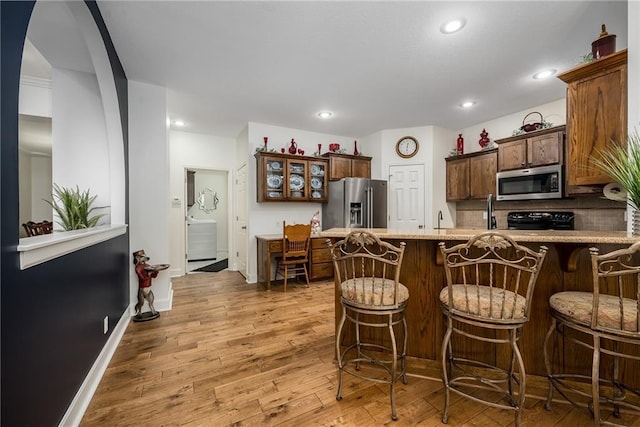 14165 Ashbury Ct, Basehor, KS 66007 - kitchen with appliances with stainless steel finishes, wood finished floors, a peninsula, a breakfast bar, and recessed lighting