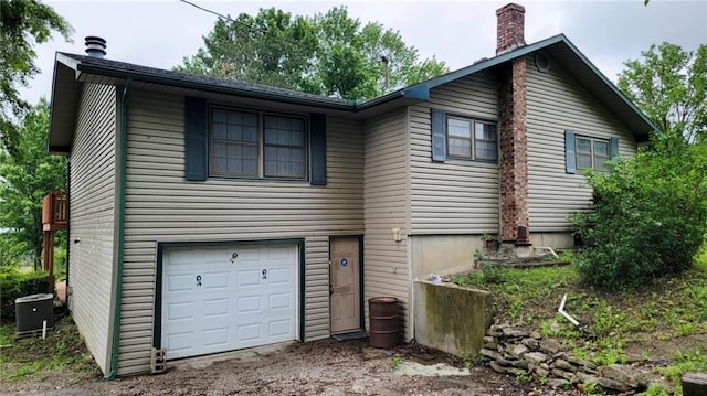 1045 Yale Rd, Mapleton, KS 66754 - view of front of house with an attached garage, a chimney, cooling unit, and driveway