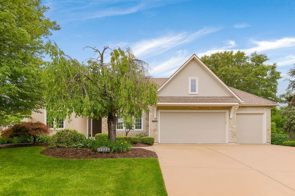 12337 Westgate St, Overland Park, KS 66213 - view of front of property with a garage, concrete driveway, a front yard, stucco siding, and stone siding