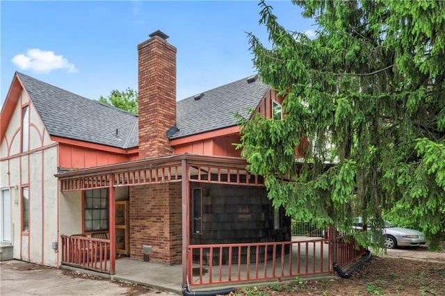 803 E College St, Independence, MO 64050 - rear view of house featuring roof with shingles, a chimney, a porch, brick siding, and board and batten siding