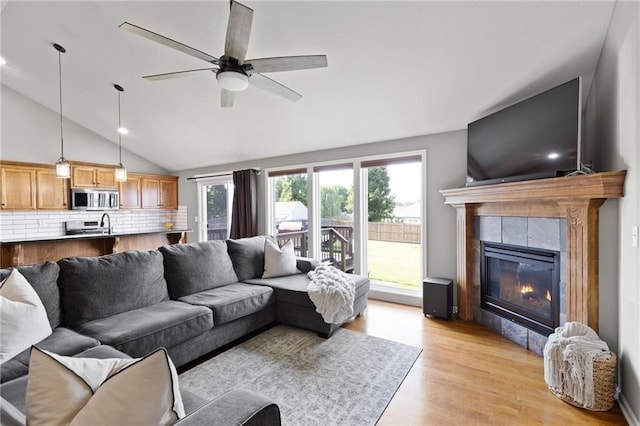 16910 Juniper Dr, Basehor, KS 66007 - living area with light wood finished floors, vaulted ceiling, ceiling fan, and a tile fireplace