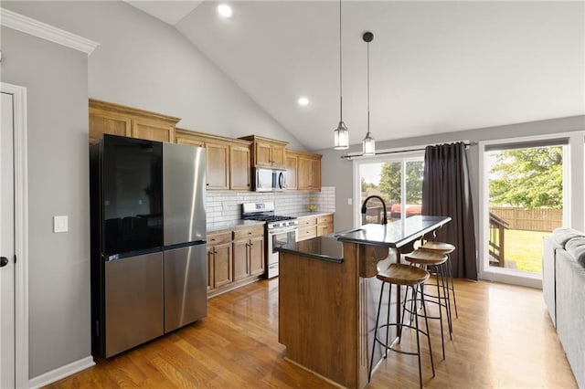 16910 Juniper Dr, Basehor, KS 66007 - kitchen with stainless steel appliances, vaulted ceiling, light wood-style floors, a breakfast bar, and backsplash