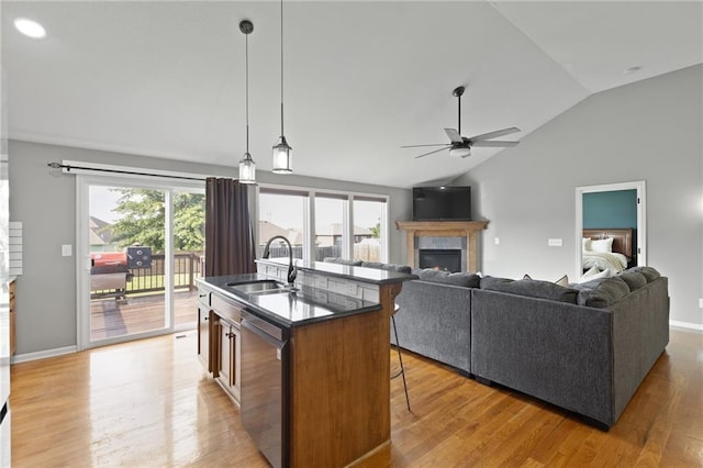 16910 Juniper Dr, Basehor, KS 66007 - kitchen with stainless steel dishwasher, a lit fireplace, ceiling fan, vaulted ceiling, and a kitchen breakfast bar