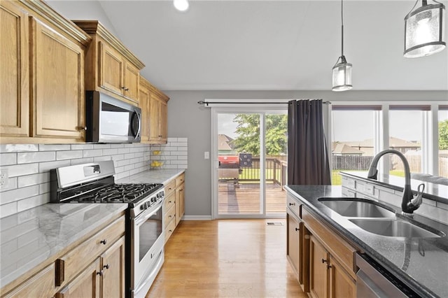 16910 Juniper Dr, Basehor, KS 66007 - kitchen with appliances with stainless steel finishes, decorative backsplash, light wood-type flooring, hanging light fixtures, and dark stone counters