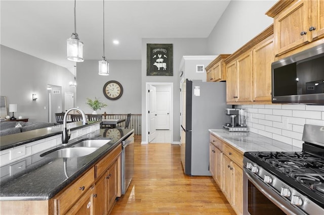 16910 Juniper Dr, Basehor, KS 66007 - kitchen featuring appliances with stainless steel finishes, decorative backsplash, light wood-type flooring, dark stone countertops, and pendant lighting