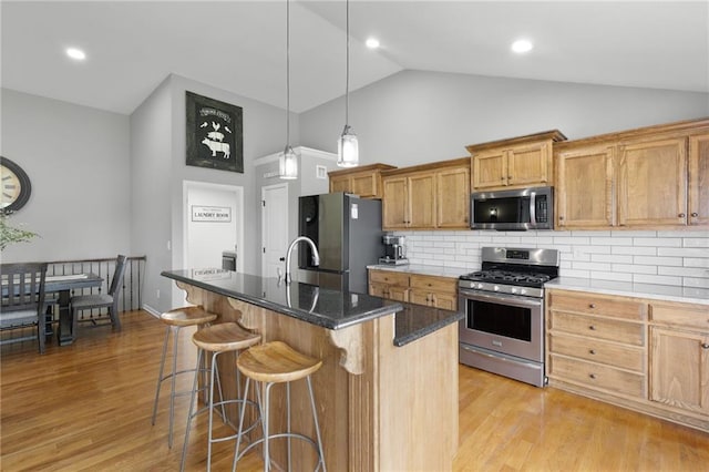 16910 Juniper Dr, Basehor, KS 66007 - kitchen with appliances with stainless steel finishes, high vaulted ceiling, a breakfast bar, backsplash, and light wood-style floors