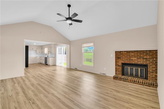 11704 E 76th Ter, Raytown, MO 64138 - unfurnished living room featuring lofted ceiling, ceiling fan, light wood-style floors, and a brick fireplace