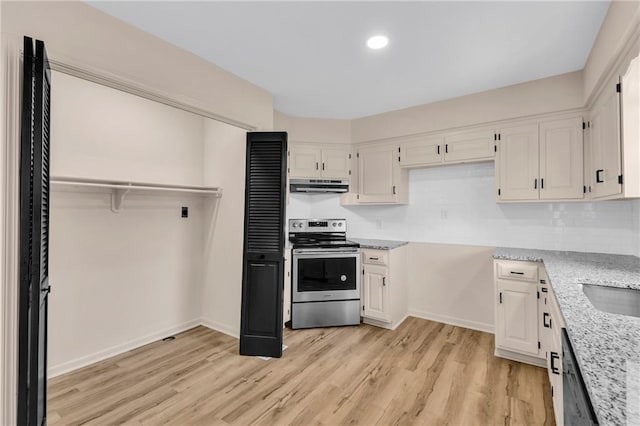 11704 E 76th Ter, Raytown, MO 64138 - kitchen with stainless steel electric range, under cabinet range hood, white cabinetry, light wood-style flooring, and light stone countertops