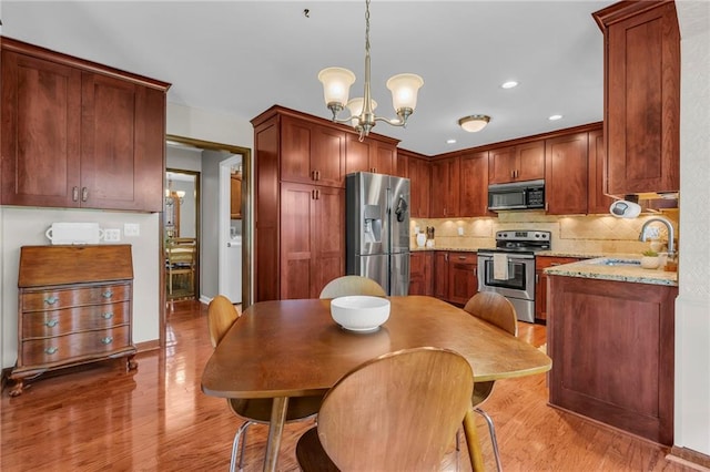 10124 Halsey St, Lenexa, KS 66215 - kitchen with appliances with stainless steel finishes, light wood-style flooring, a sink, a chandelier, and tasteful backsplash