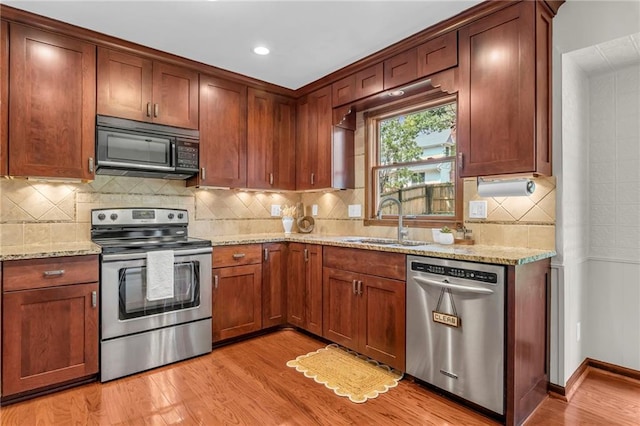 10124 Halsey St, Lenexa, KS 66215 - kitchen featuring stainless steel appliances, a sink, light wood-type flooring, light stone counters, and backsplash