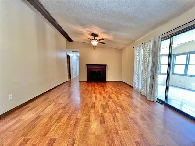 213 Morningside Pl, Independence, KS 67301 - unfurnished living room with light wood finished floors, ceiling fan, a textured ceiling, a fireplace, and baseboards