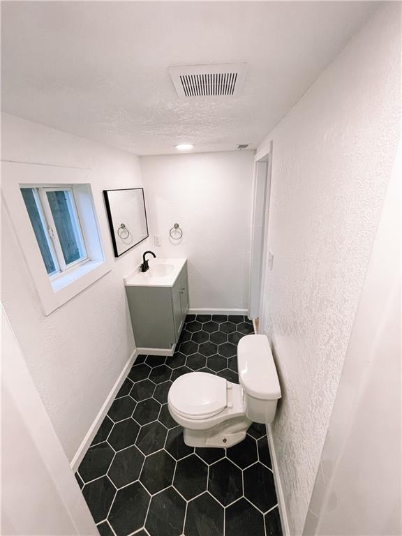 8633 N Main St, Kansas City, MO 64155 - half bath featuring toilet, vanity, tile patterned floors, and baseboards