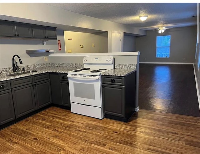 106 Saratoga St, Excelsior Springs, MO 64024 - kitchen featuring electric range, a textured ceiling, a peninsula, wood finished floors, and light stone countertops